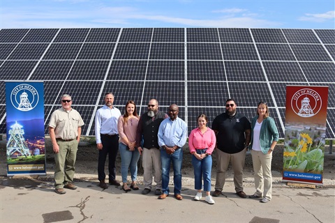City staff, Mayor Wilmot Collins and Commissioner Emily Dean standing in front of solar panels.